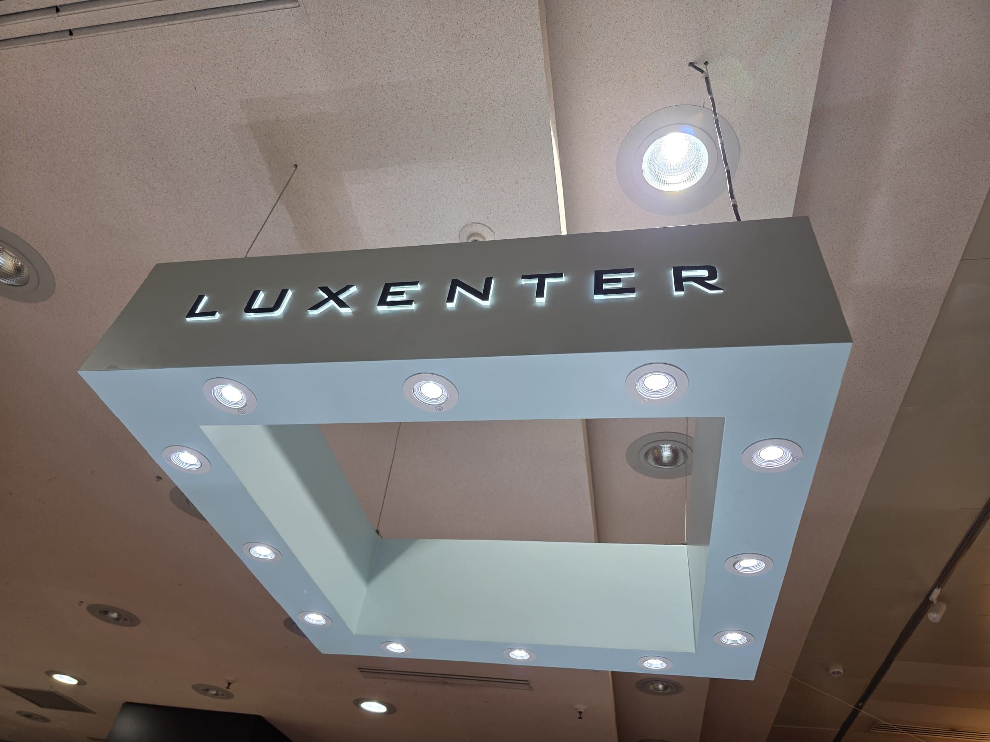 Letras iluminadas de Luxenter en un elemento suspendido interior