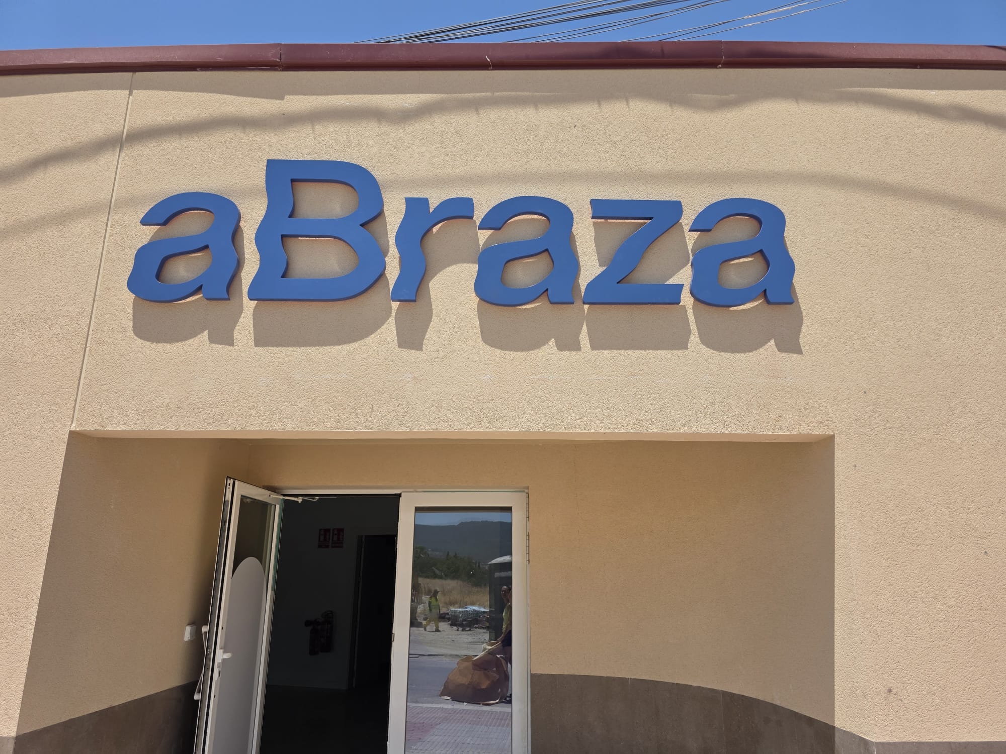 Letras corpóreas azules de aBraza en una fachada