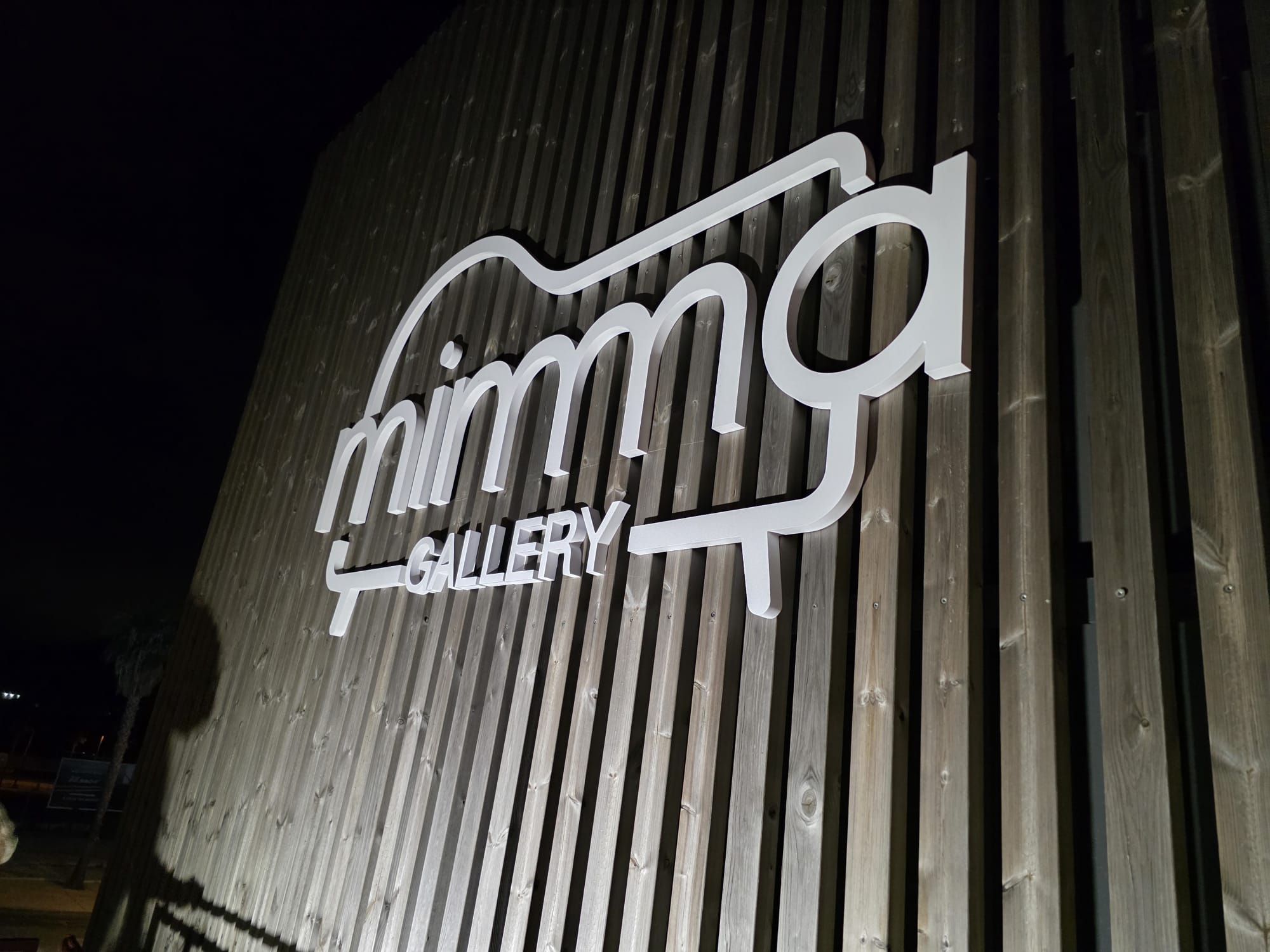Rótulo iluminado de MIMMA Gallery en una fachada