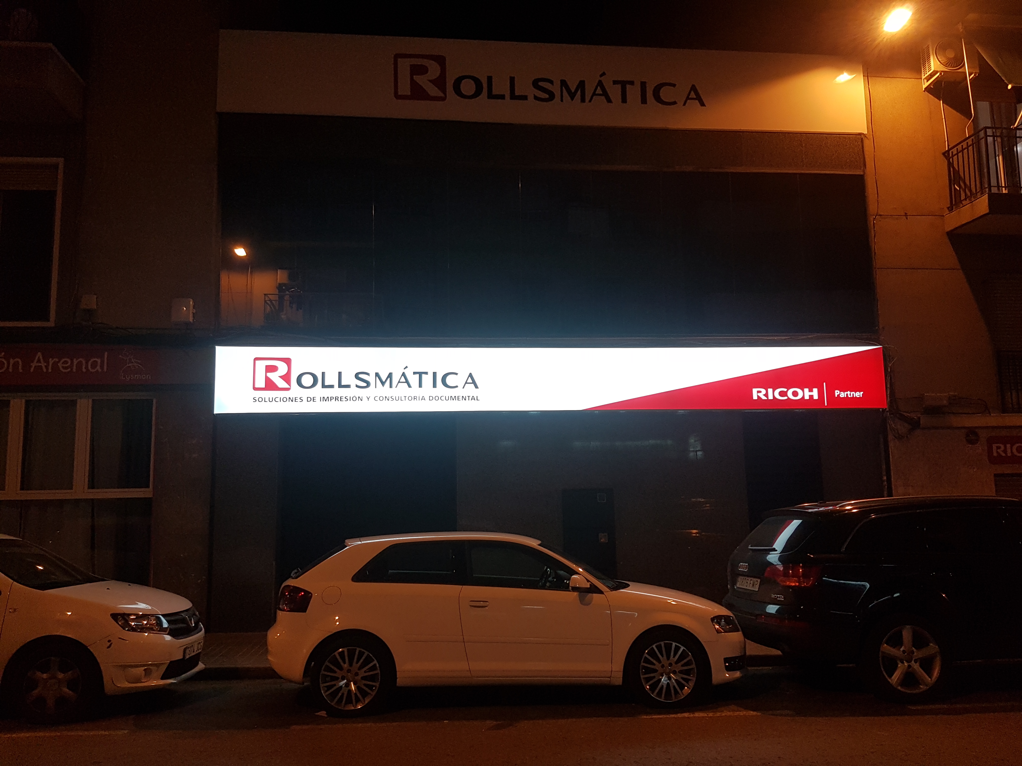 Rótulo rectangular luminoso de Rollsmática en una fachada de noche