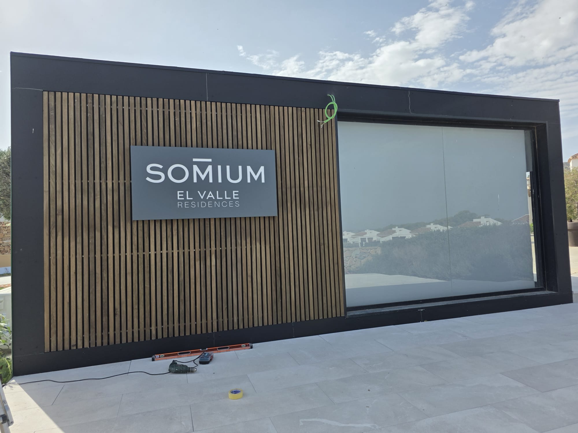Rótulo de Somium visible en una fachada de lamas oscuras