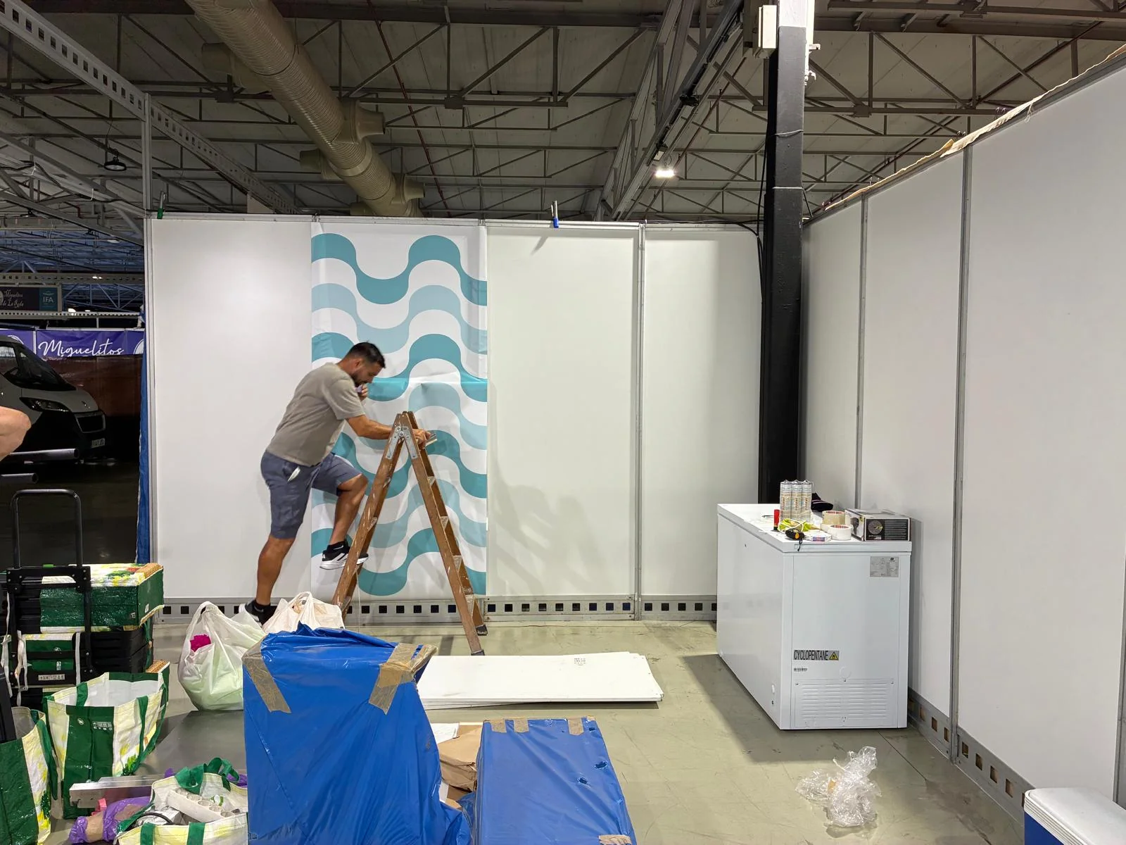 Persona colocando la gráfica de ondas en una pared del stand de Mila